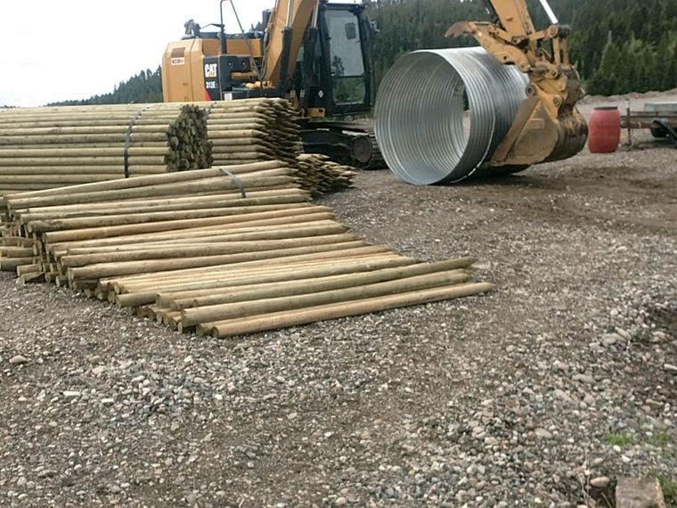 Excavator, culvert and pole stock staged for access road work