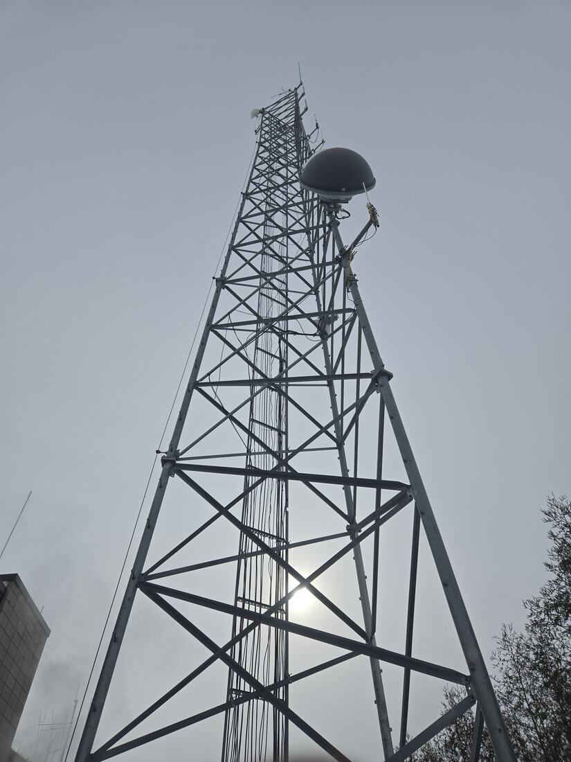 Lattice tower carrying a radome and antennas against a low sun