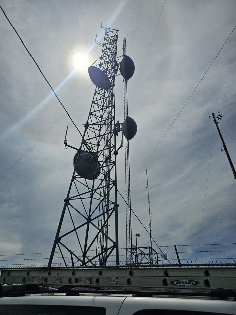 Tower carrying paired radomes and microwave dishes above a service truck